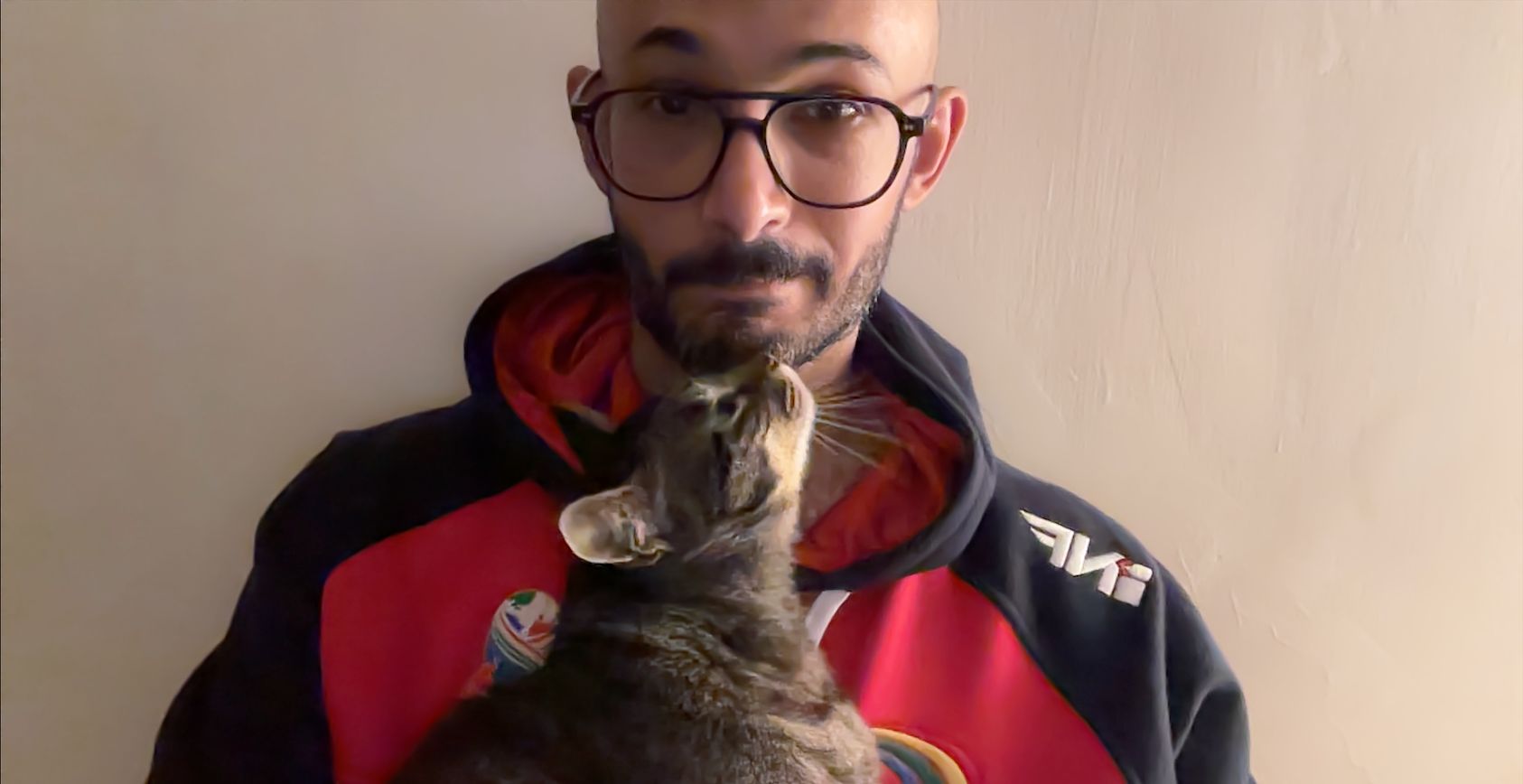 A man looking towards the camera with a skeptical face. A cat looks up at him lovingly.